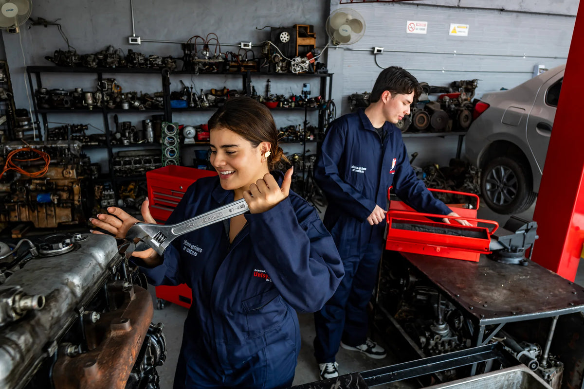 Estudiantes de Unisystem usan herramientas y revisan un motor en el taller.
