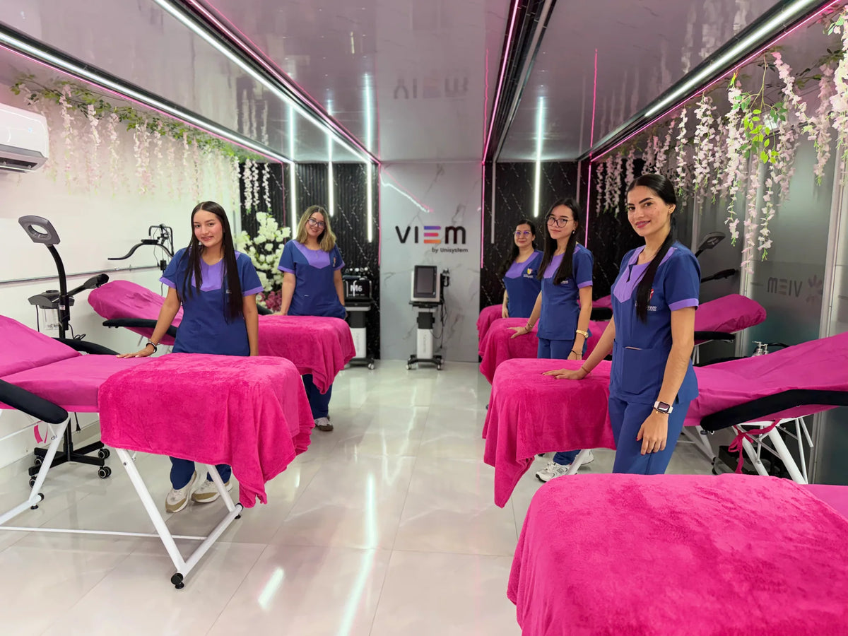 Estudiantes en el laboratorio de Cosmetología de Unisystem, junto a las camillas de práctica.