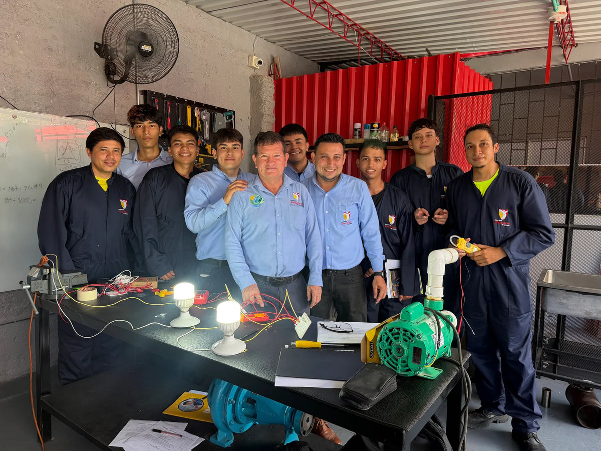 Grupo de Unisystem junto a un circuito de iluminación y un equipo de bombeo en el taller.
