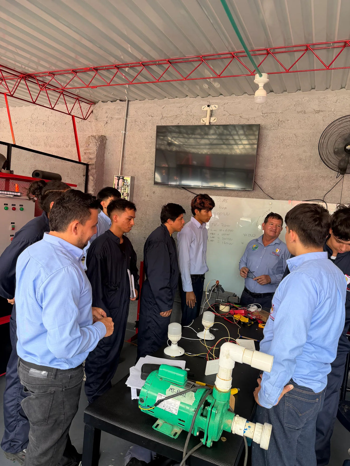 Estudiantes de Unisystem aplican conocimientos con un montaje eléctrico y un equipo de bombeo en el taller.