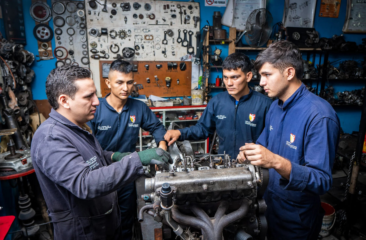 Docente y estudiantes de Unisystem alrededor de un motor durante una actividad de taller.