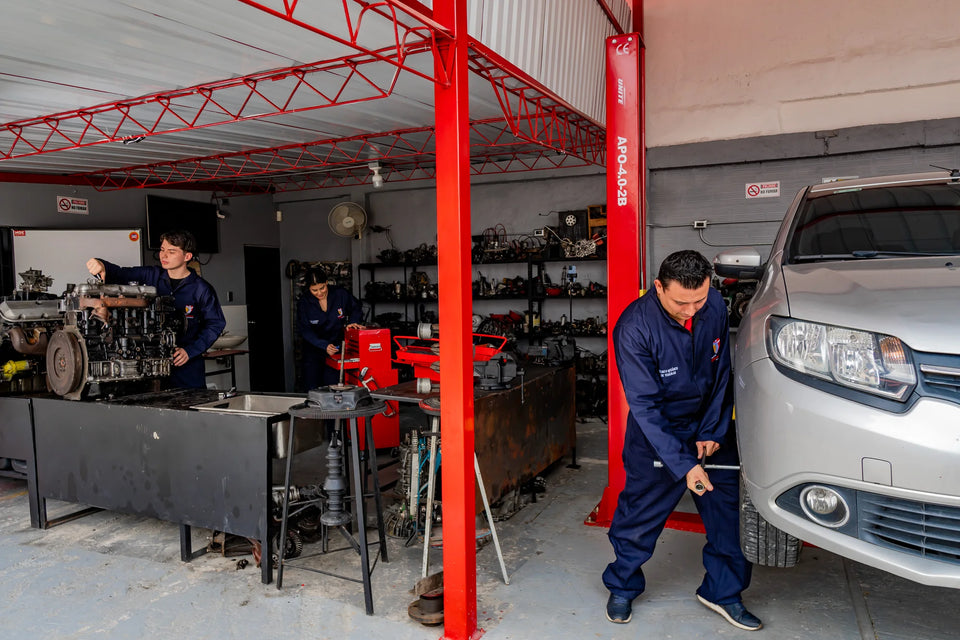 Estudiantes de Unisystem trabajando en un taller con automóvil, motores y herramientas.