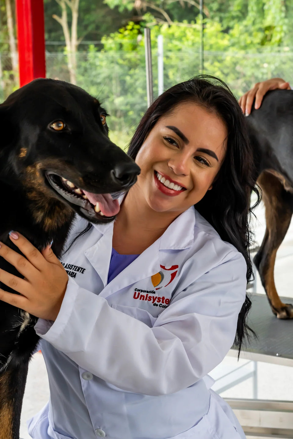 Estudiante de Unisystem junto a un perro en un espacio de atención veterinaria.